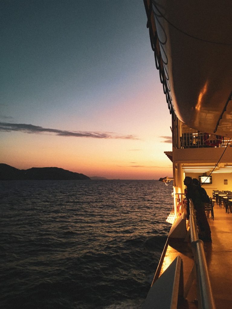 a person standing on a boat watching the sunset